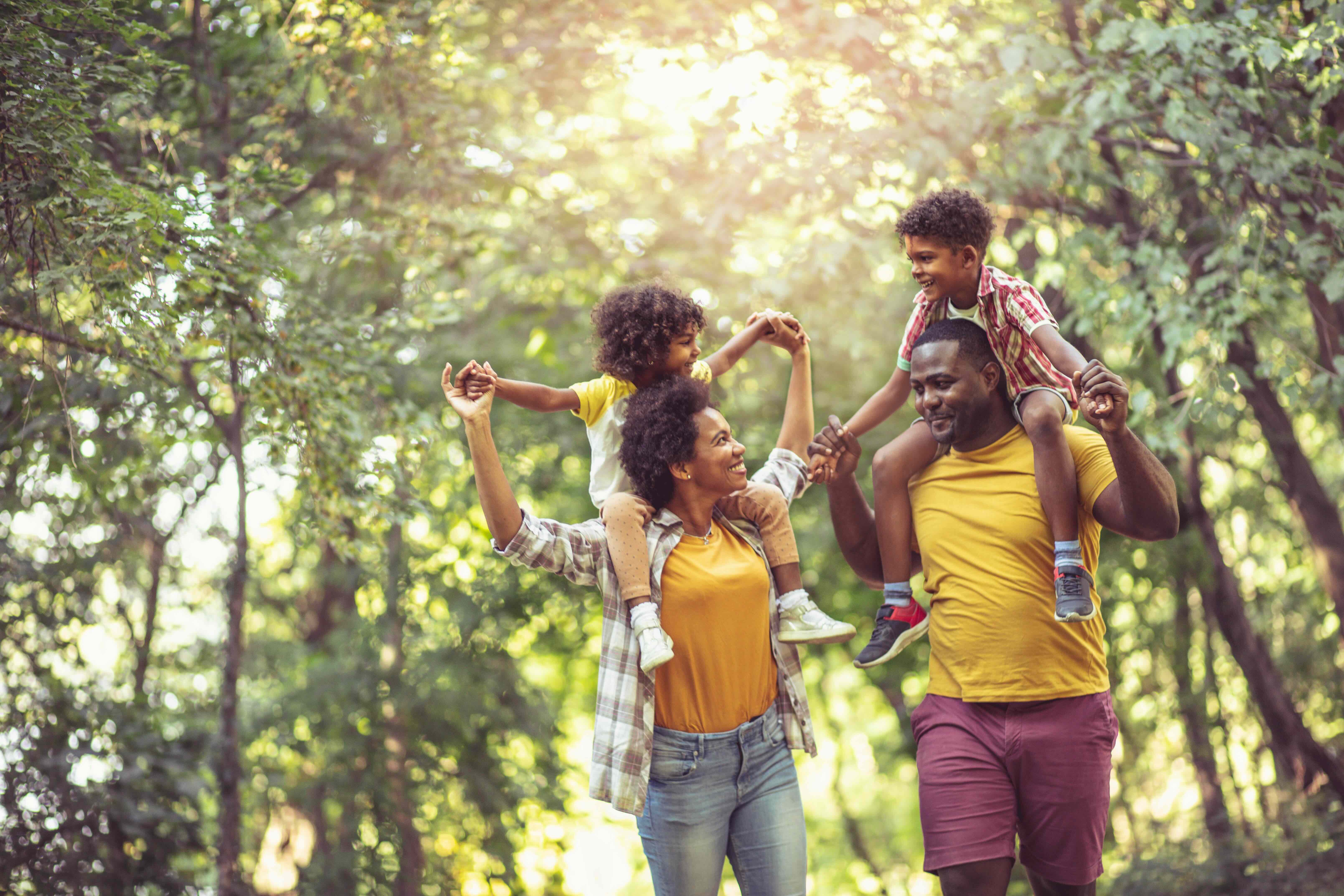 Family walking on a trail with kids on shoulders